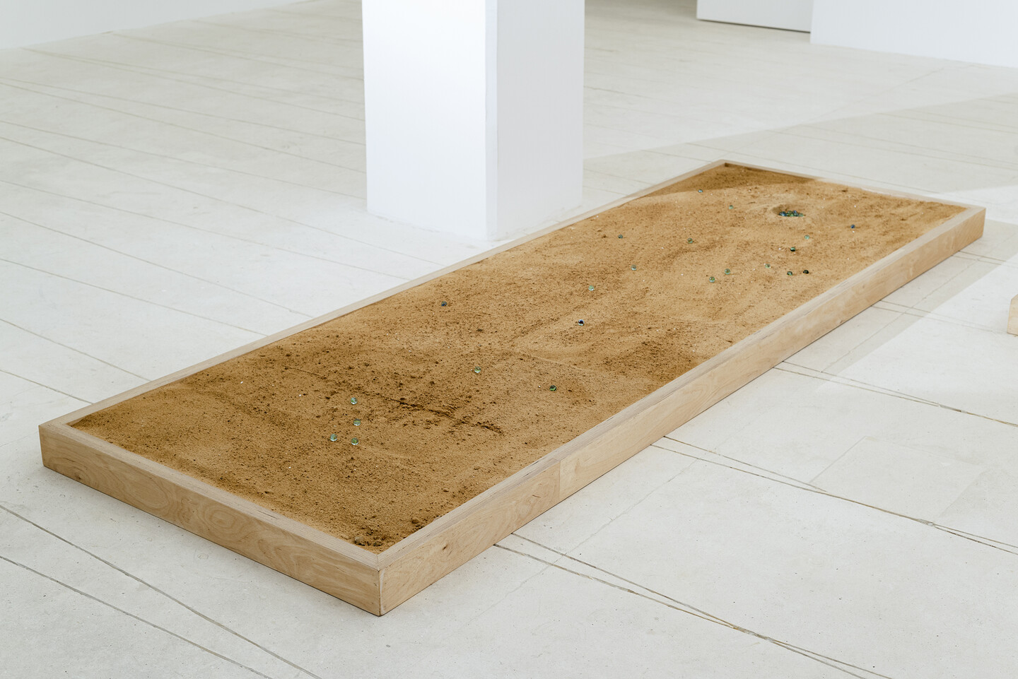 Marbles, 2024, 7 heated glass marbles, sand, wood, 300 × 100 × 10 cm