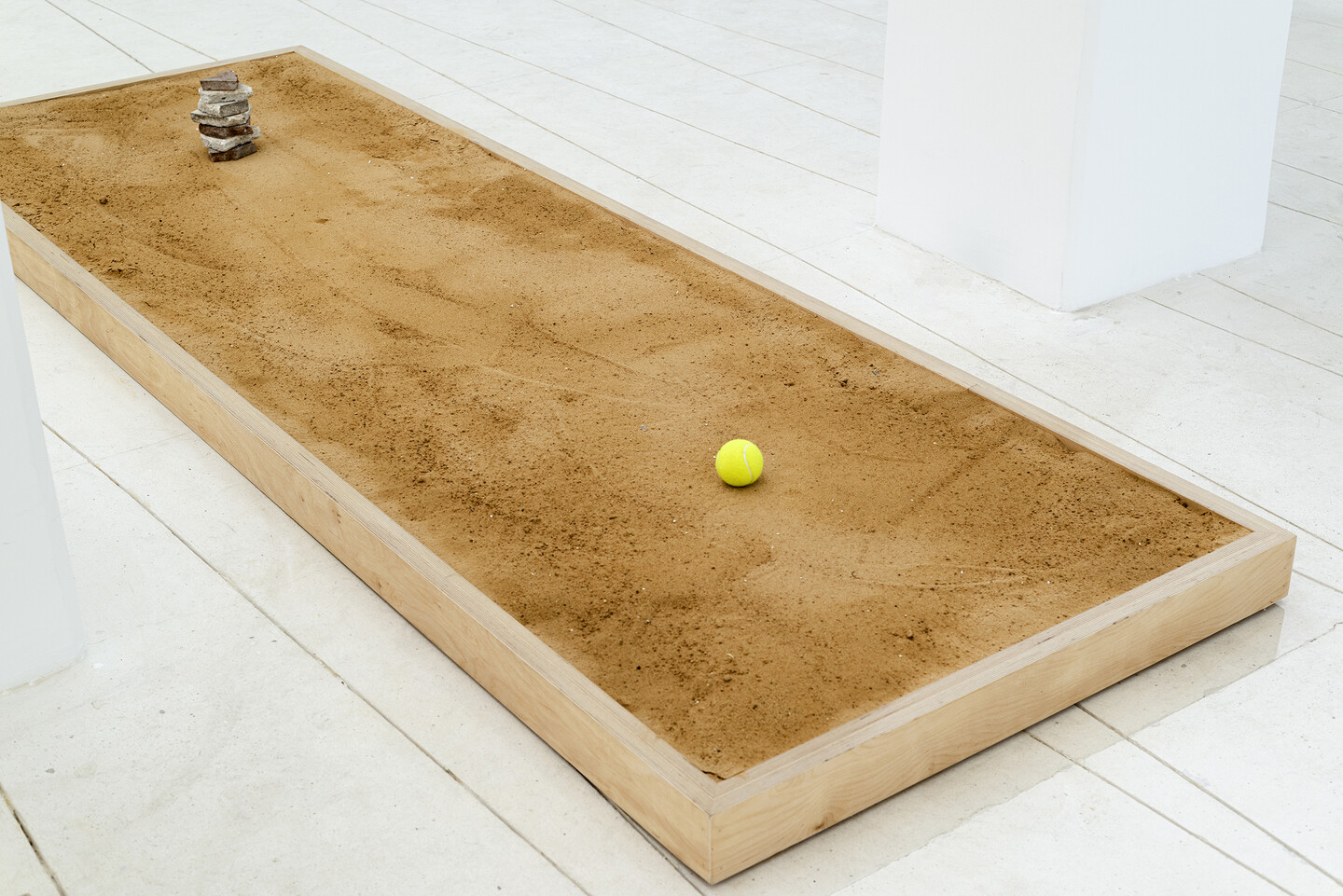 Seven Stones, 2024, 7 stones, tennis ball, sand, wood, 300 × 100 × 10 cm