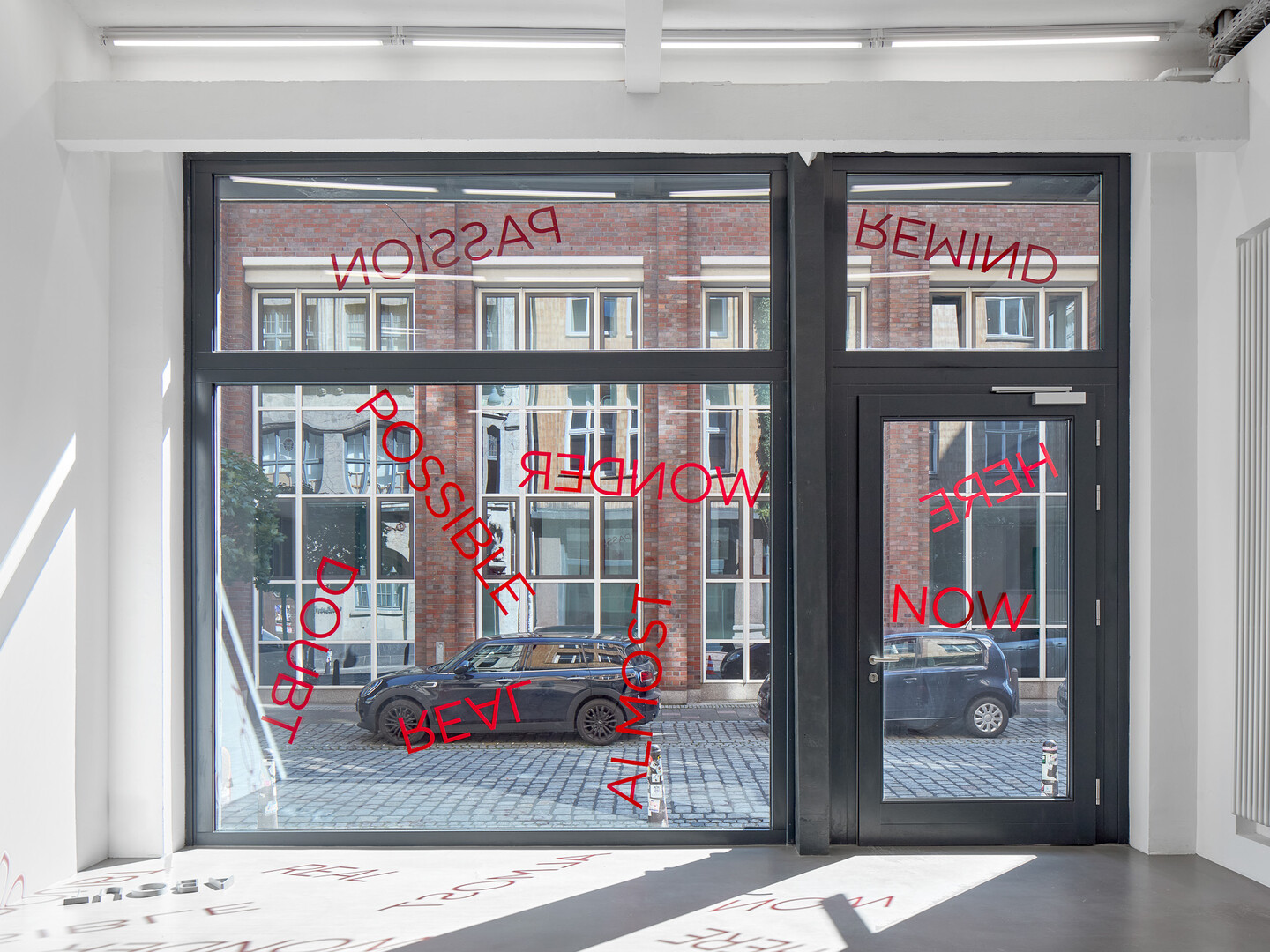 Untitled, 2024, 19 red foil words on window, Dimensions variable